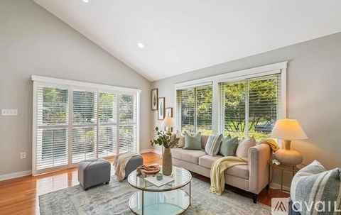 A living room with a glass coffee table and a couch with a striped throw.