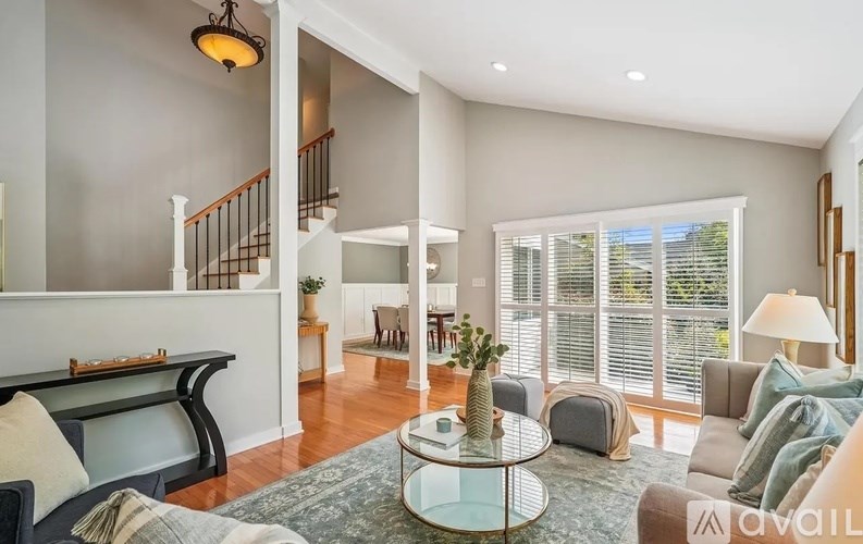 A living room with a staircase and a glass table.