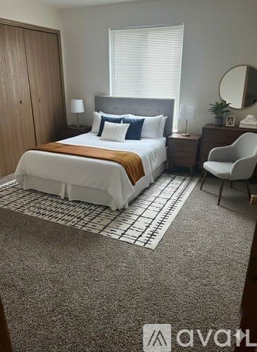 A bedroom with a bed, nightstand, chair, and a rug.