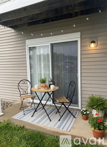 A patio with a table and chairs and a striped rug.