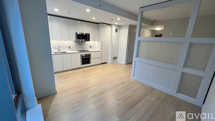 A modern kitchen with wooden floors and white cabinetry.