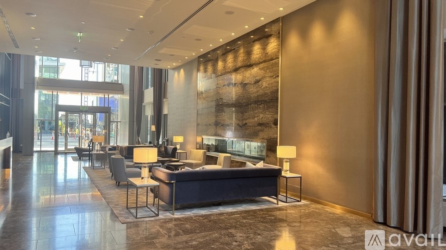 A spacious hotel lobby with a large stone wall and a long black sofa.