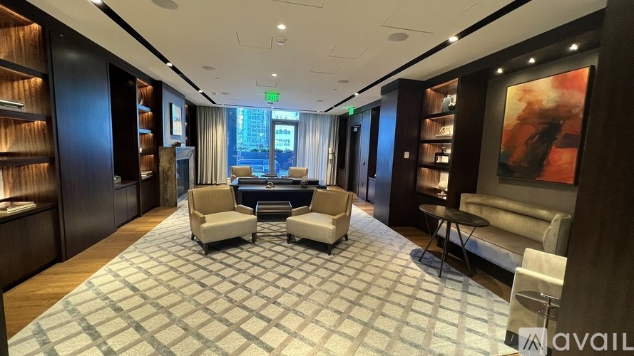 A spacious living room with a large rug and a painting on the wall.