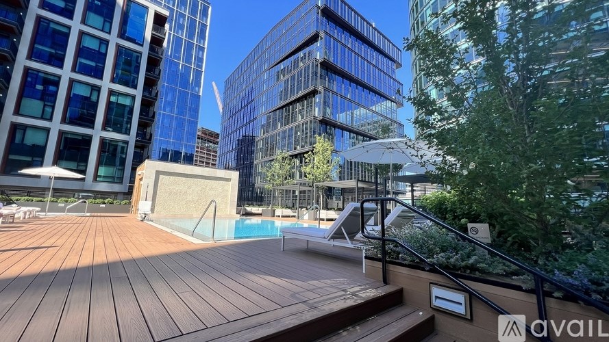 A wooden deck with a pool and a building in the background.