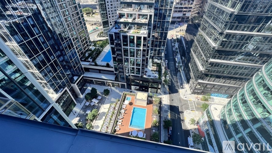 A view from a high-rise building looking down at a pool surrounded by buildings.