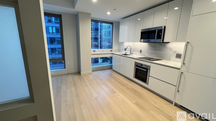 A modern kitchen with white cabinets and a wooden floor.