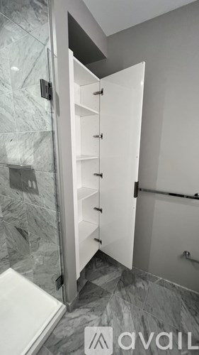 A white cabinet with drawers is open in a bathroom.