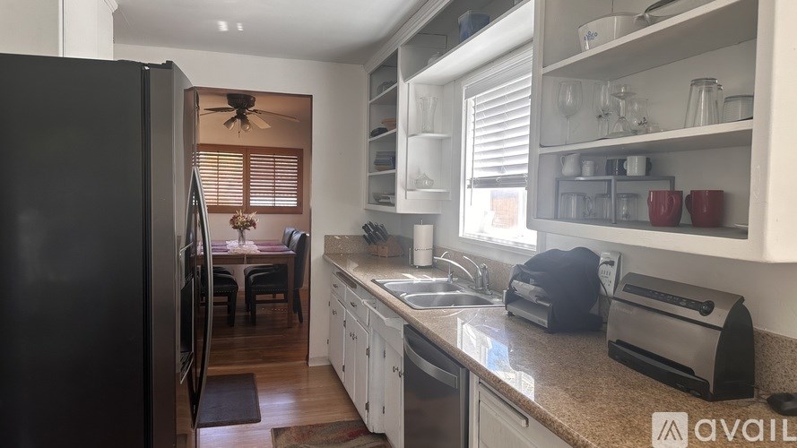 A kitchen with a black refrigerator and white cabinets.