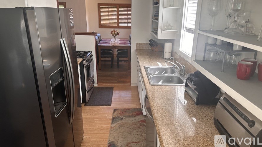 A kitchen with a refrigerator, sink, and dining table.