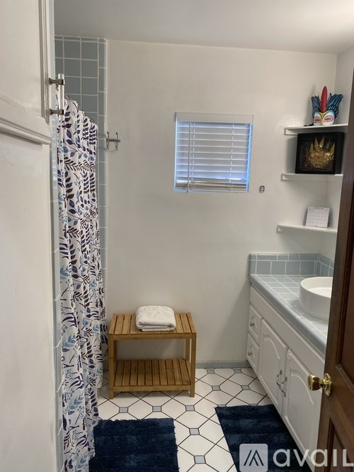 A bathroom with a shower curtain and a wooden stool.
