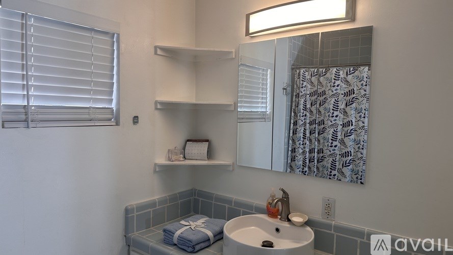 A bathroom with a white sink and a shower curtain with a pattern.