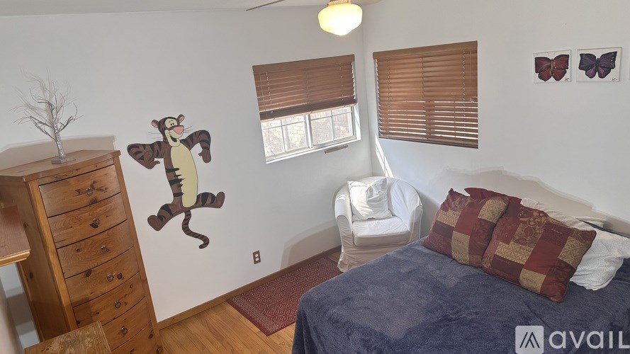 A bedroom with a bed, a chair, a dresser, and a wall decal of a monkey.