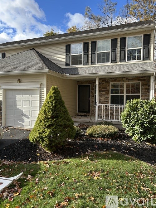 A house with a white garage door and a small tree in front.