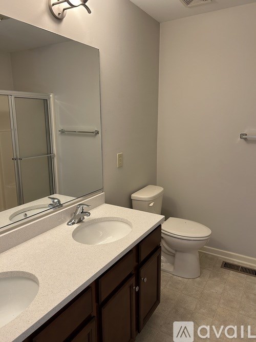 A bathroom with a toilet, sink, and mirror.
