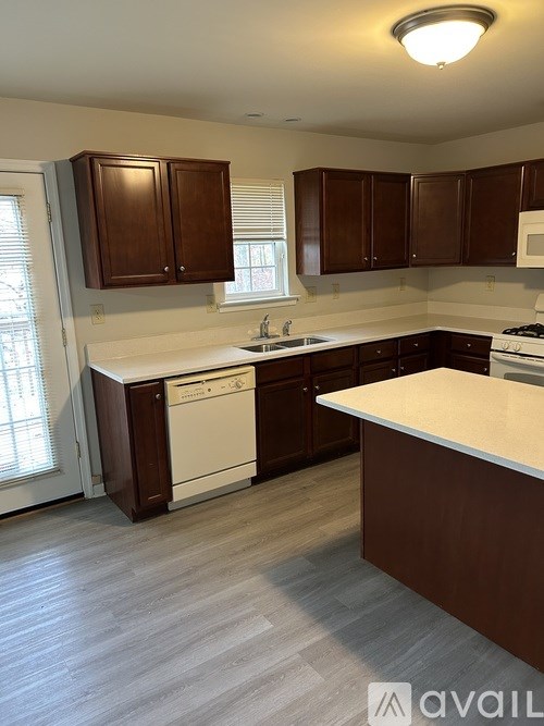 A kitchen with brown cabinets and a white dishwasher.