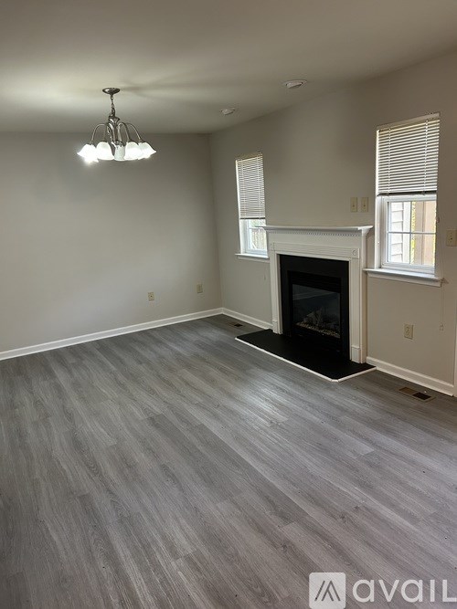 A living room with a fireplace and grey flooring.
