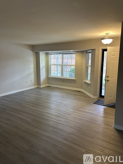 A room with wooden flooring and a door on the right side.
