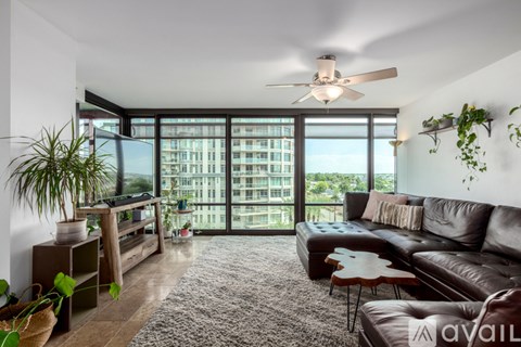 A living room with a brown leather couch and a ceiling fan.