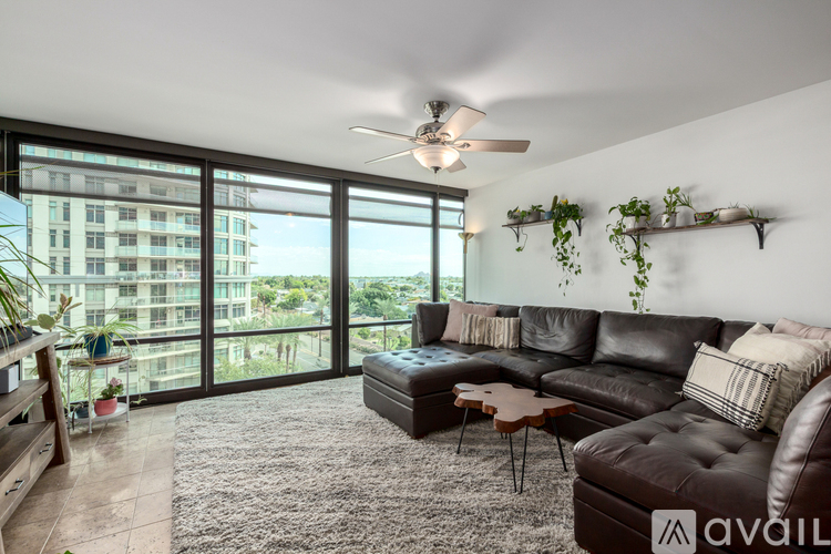 A living room with a black couch and a ceiling fan.