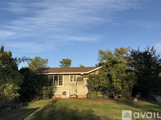 A house with a brown roof and a white door is surrounded by greenery.