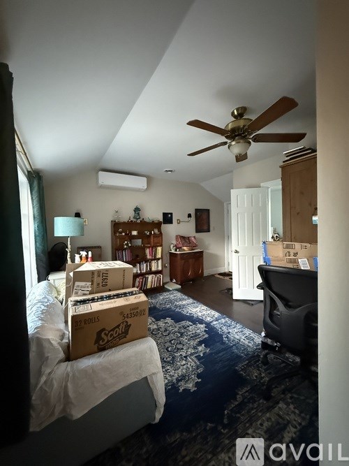 A room with a ceiling fan and boxes on the floor.