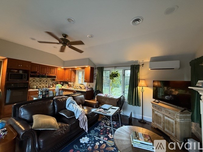 A living room with a black leather couch and a ceiling fan.