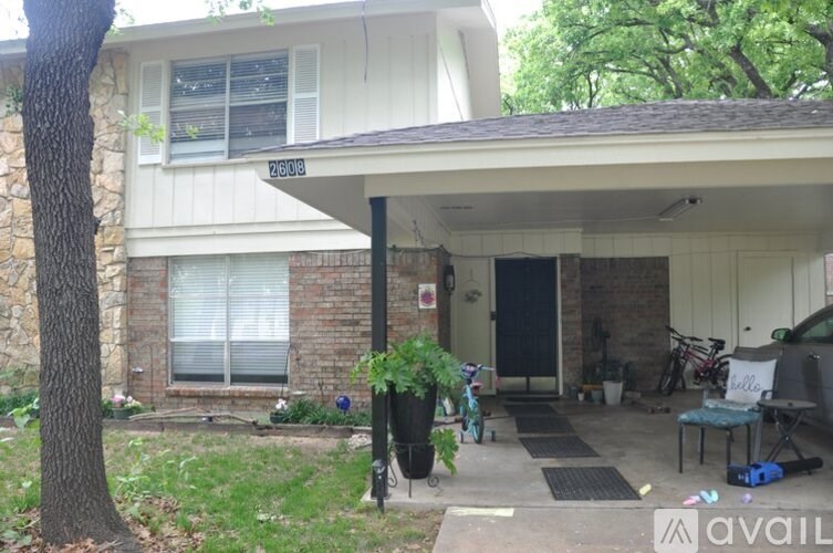 A house with a porch and a tree in front of it.