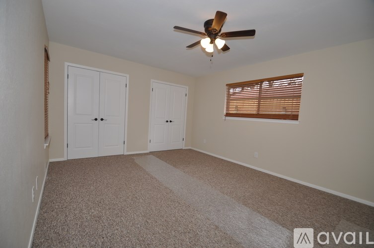 A room with a ceiling fan and carpeted floor.