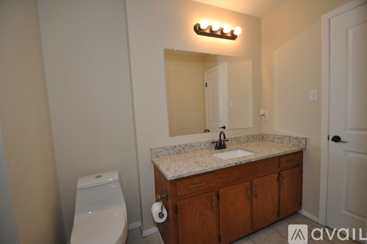 A bathroom with a sink, toilet, and mirror.