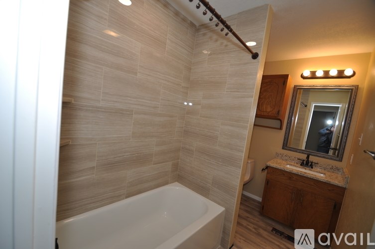 A bathroom with a tub, sink, and mirror.
