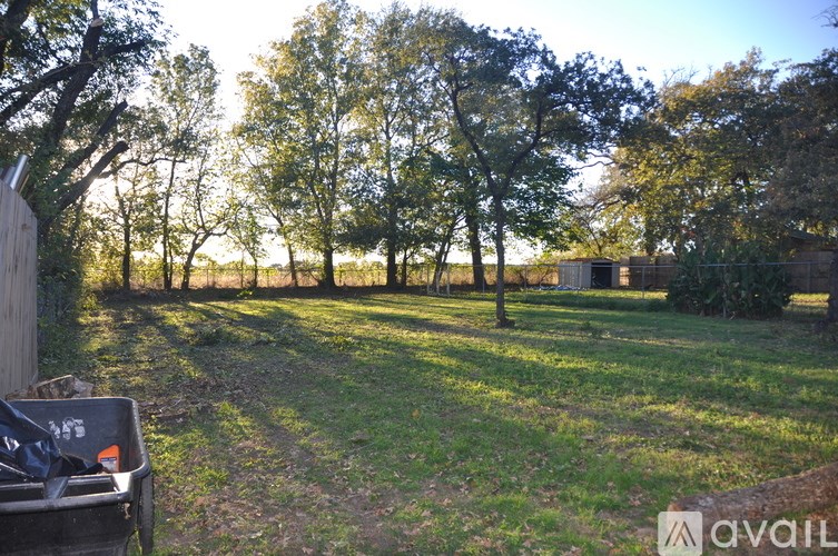 A field with trees and a fence with a sign that says "available".