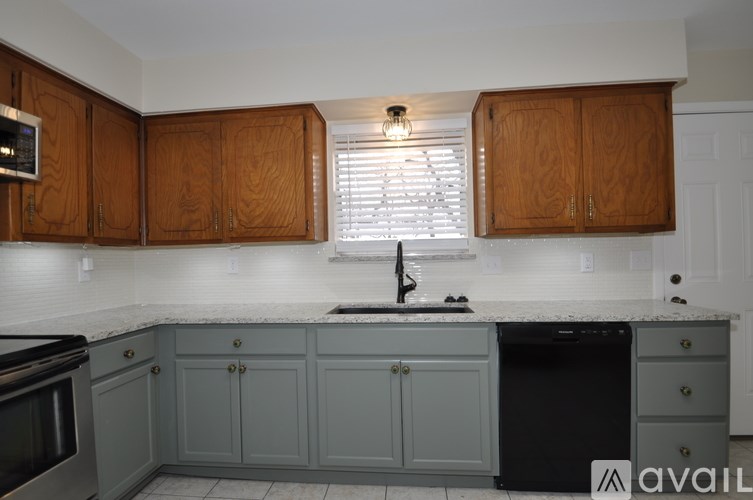 A kitchen with wooden cabinets and a black dishwasher.