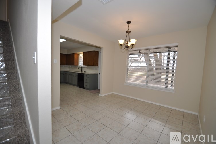 A room with a chandelier and a window with blinds.