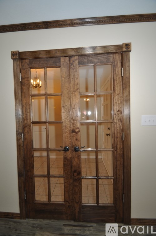 A wooden door with a glass panel and a chandelier above it.