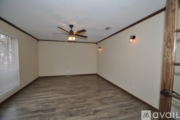 A room with a ceiling fan and wooden flooring.