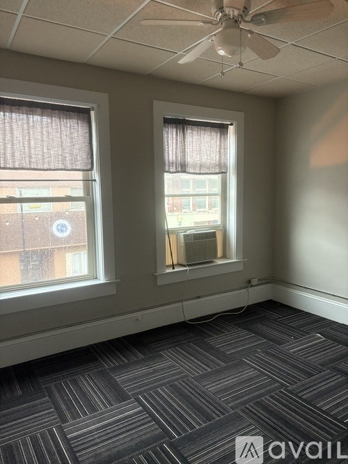 A room with a carpeted floor and two windows.