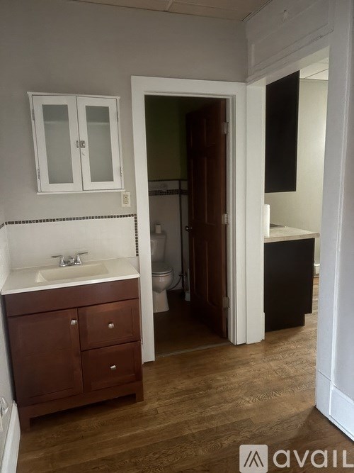 A bathroom with a sink, toilet, and wooden floors.
