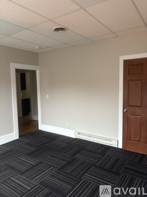 A room with a carpeted floor and a wooden door.