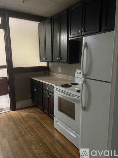 A kitchen with a white refrigerator and black cabinets.