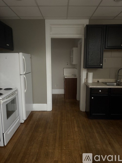 A kitchen with white appliances and dark wood floors.