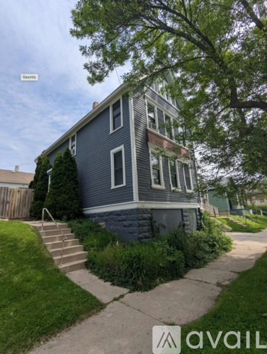A house with a blue exterior and a tree in front.
