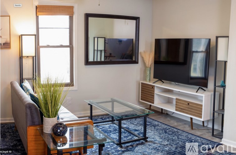 A living room with a couch, a glass coffee table, a television, and a mirror.