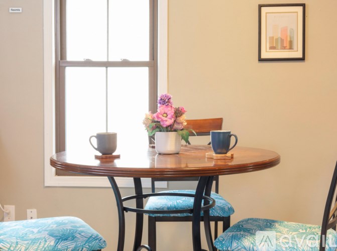 A dining table with chairs and a vase of flowers.
