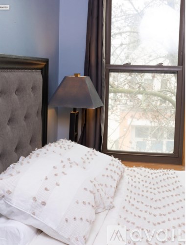 A bed with a white pillow and a grey headboard.