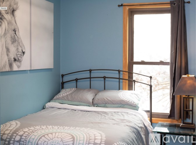 A bed with a white and grey patterned comforter sits in a room with blue walls.