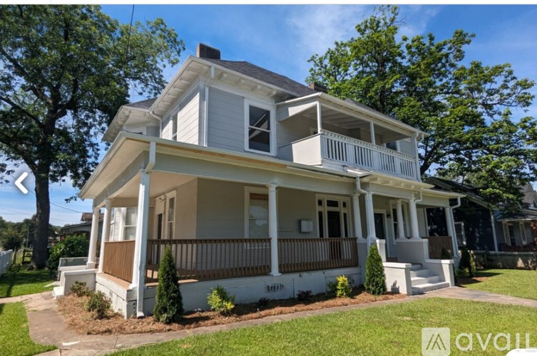 A two-story house with a white exterior and a balcony on the second floor.