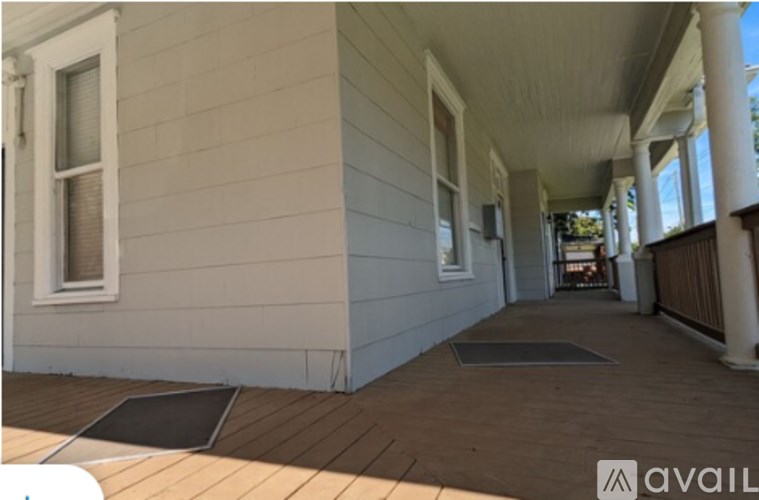 A porch with a wooden floor and white walls.