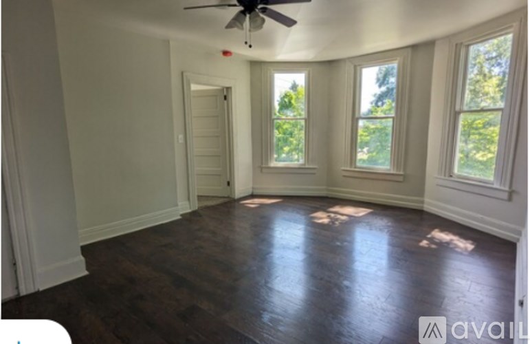 A room with a ceiling fan and three windows.