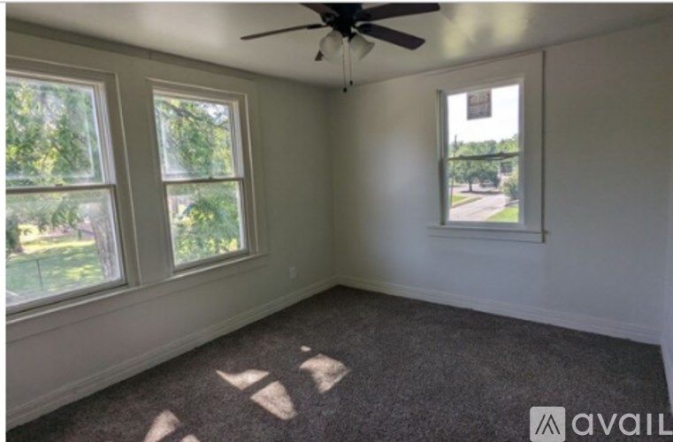 A room with a ceiling fan and two windows.