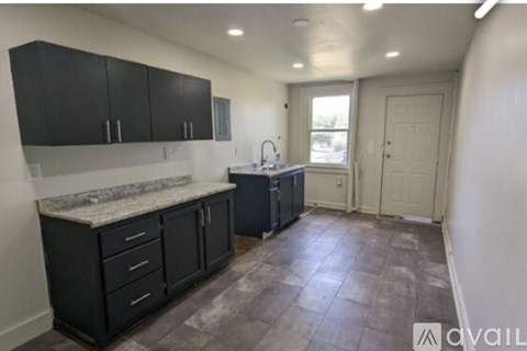 A kitchen with black cabinets and a marble countertop.
